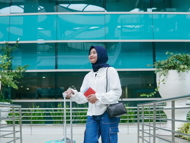 A woman wearing a headscarf carrying luggage.