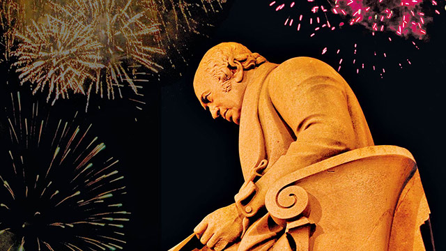 low shot of James Watt statue with fireworks in the background