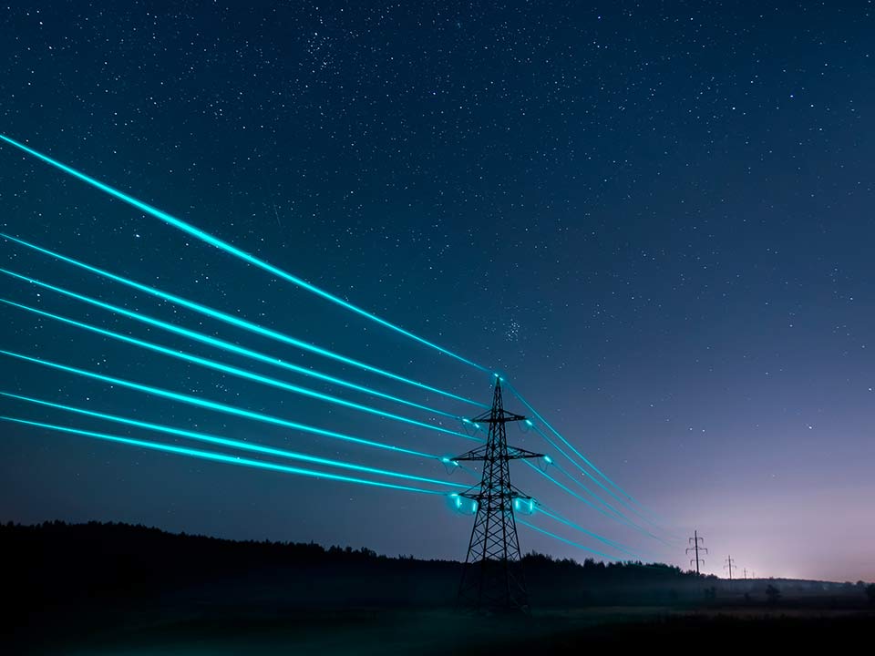 electrical towers at night with glowing blue wires
