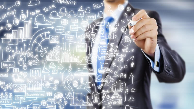 Man in suit writing on glass board