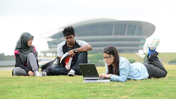 Malaysian students sitting on grass