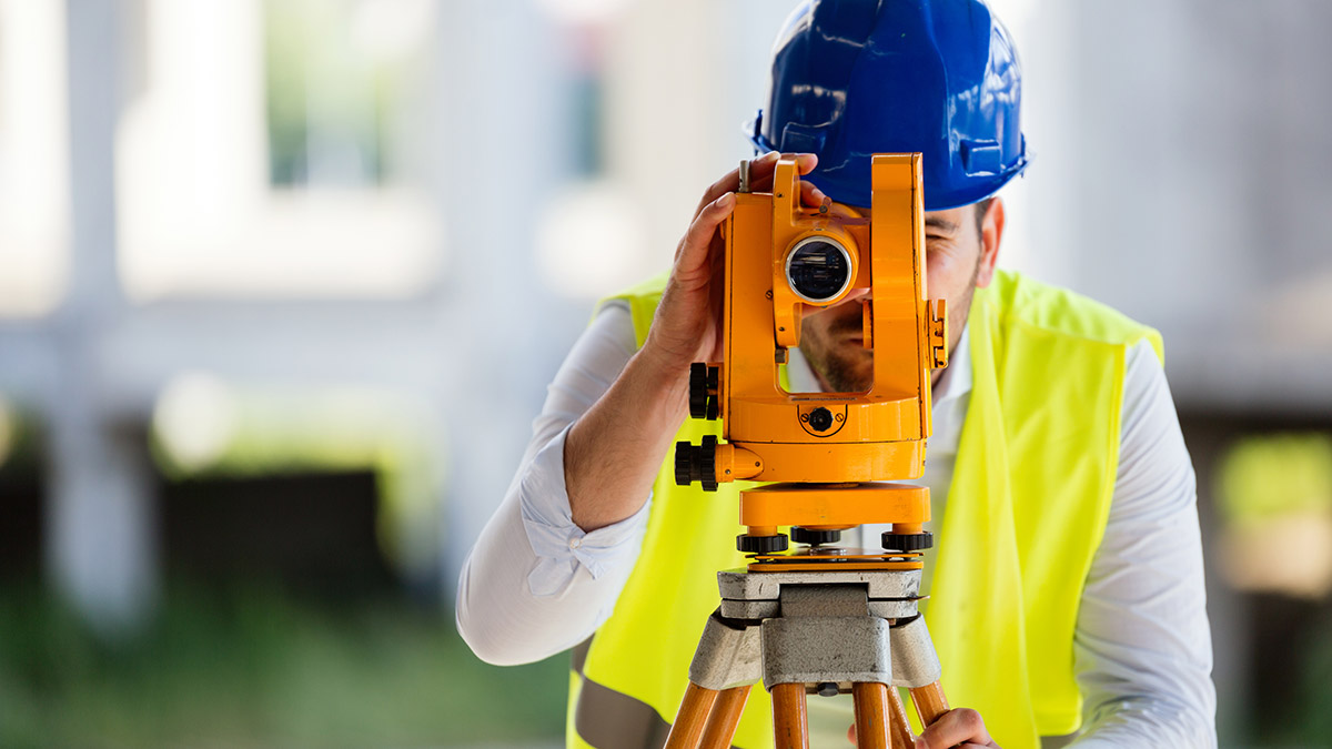 Male surveyor looking through a theodolite