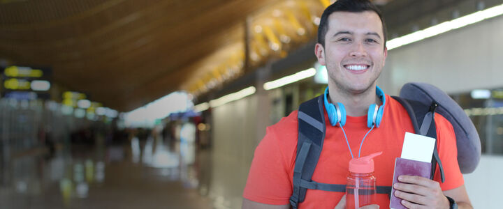 Young man holding his passport and ticket in a terminal building