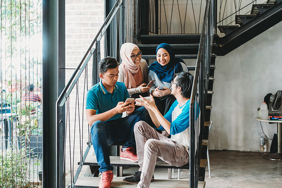 Group of young people in conversation while seated on an indoor staircase