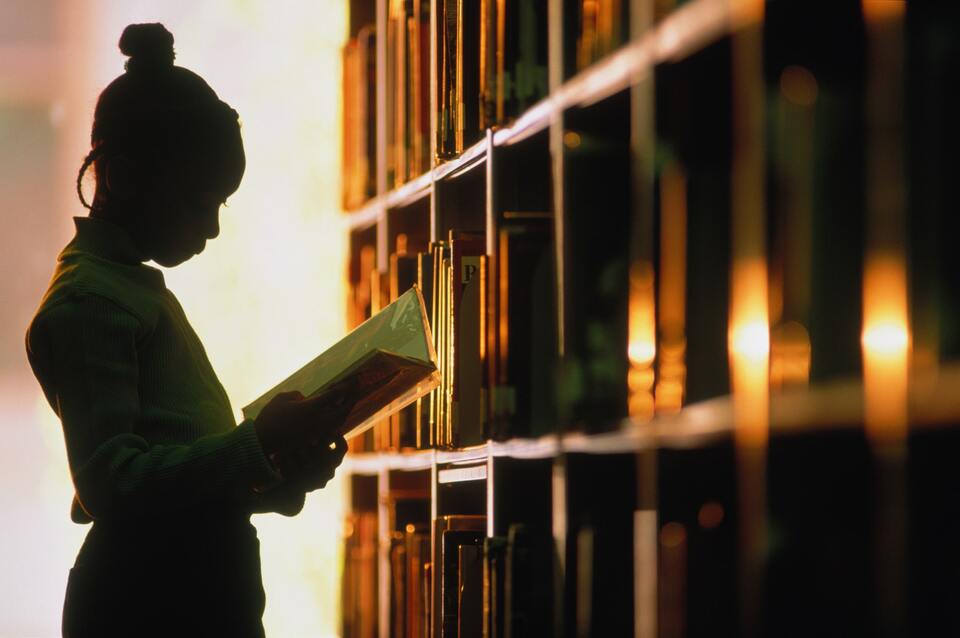 girl reading near a book shelf 