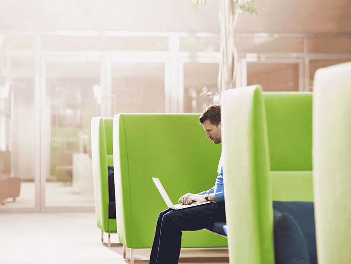 Man sitting on a green sofa using a laptop