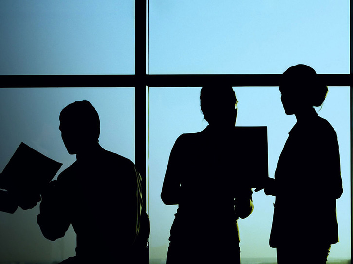 Business people silhoutted against a large glass window