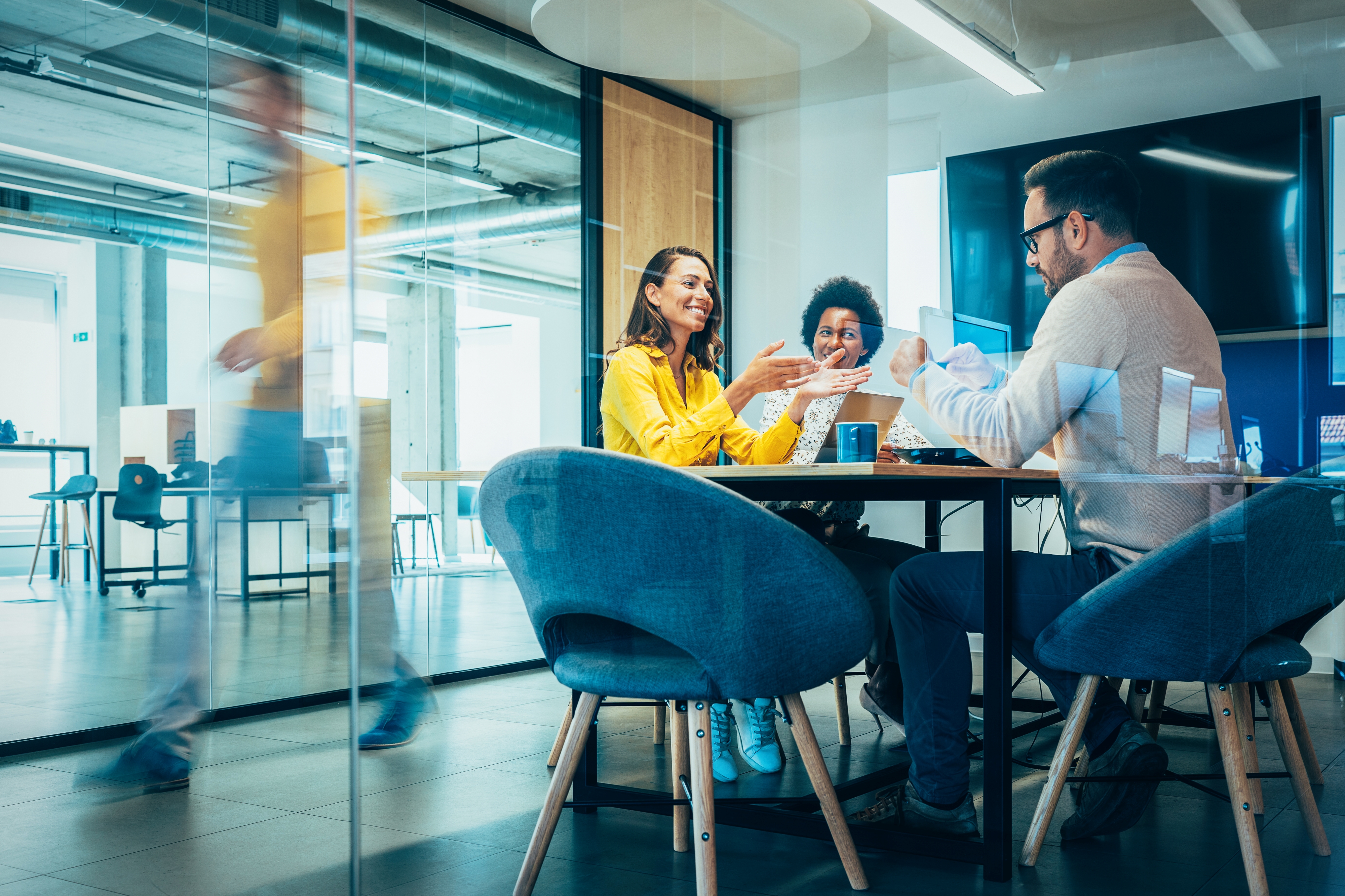 Three people seated at a meeting table in a business office.