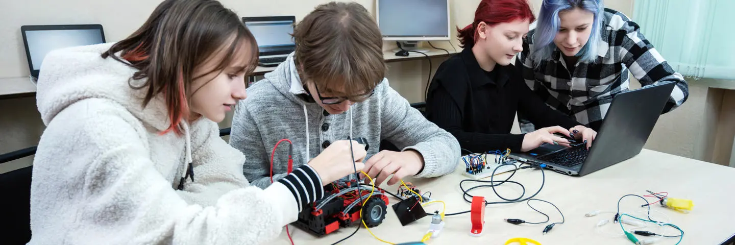Four students in school working on STEM engineering science class.