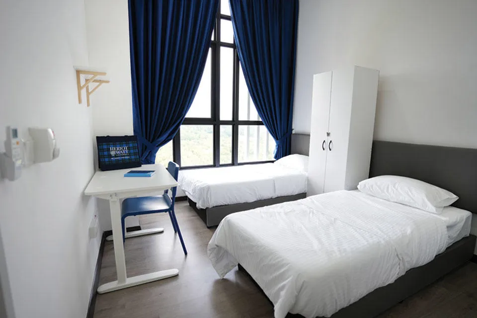 Twin Sharing En Suite Bedroom A spacious bedroom with two beds and a desk, providing a harmonious blend of rest and work areas.