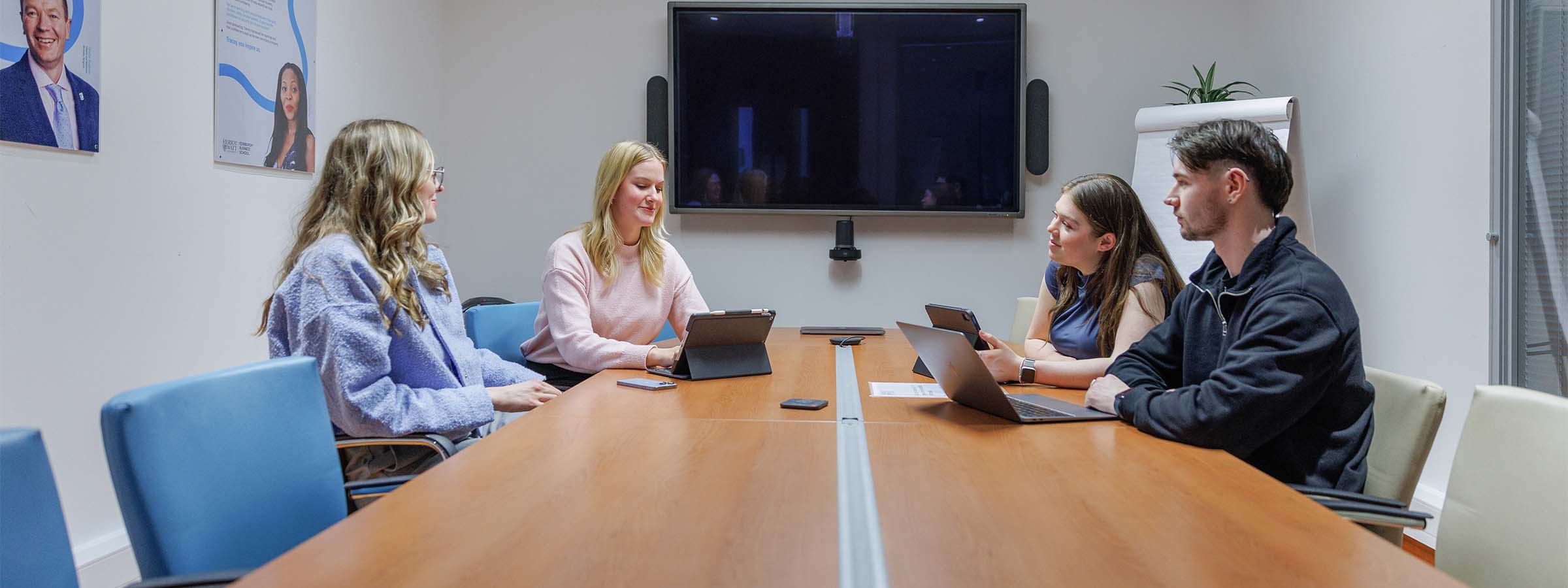 A group of students around a meeting room table