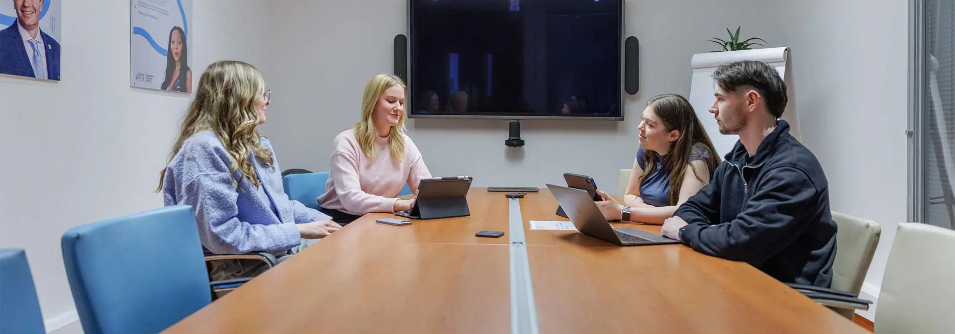 A group of students around a meeting room table