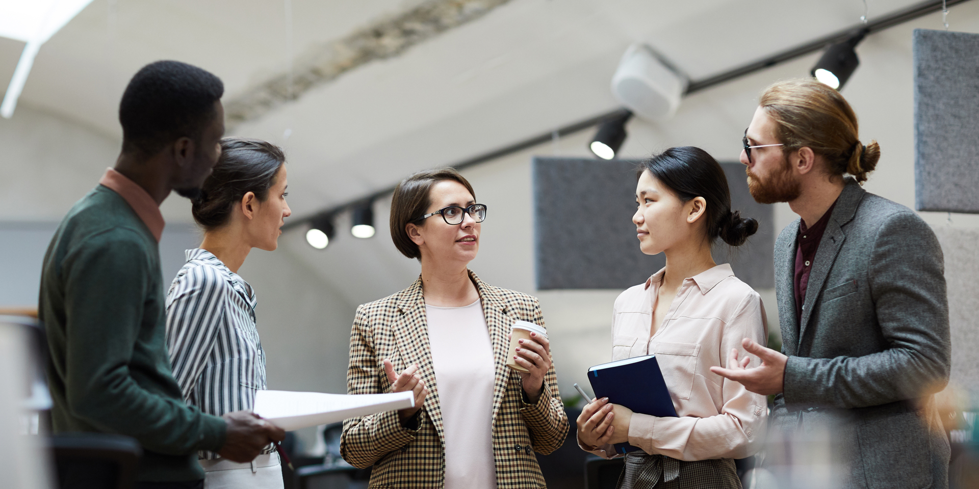 Five professionals having a discussion in a modern office.