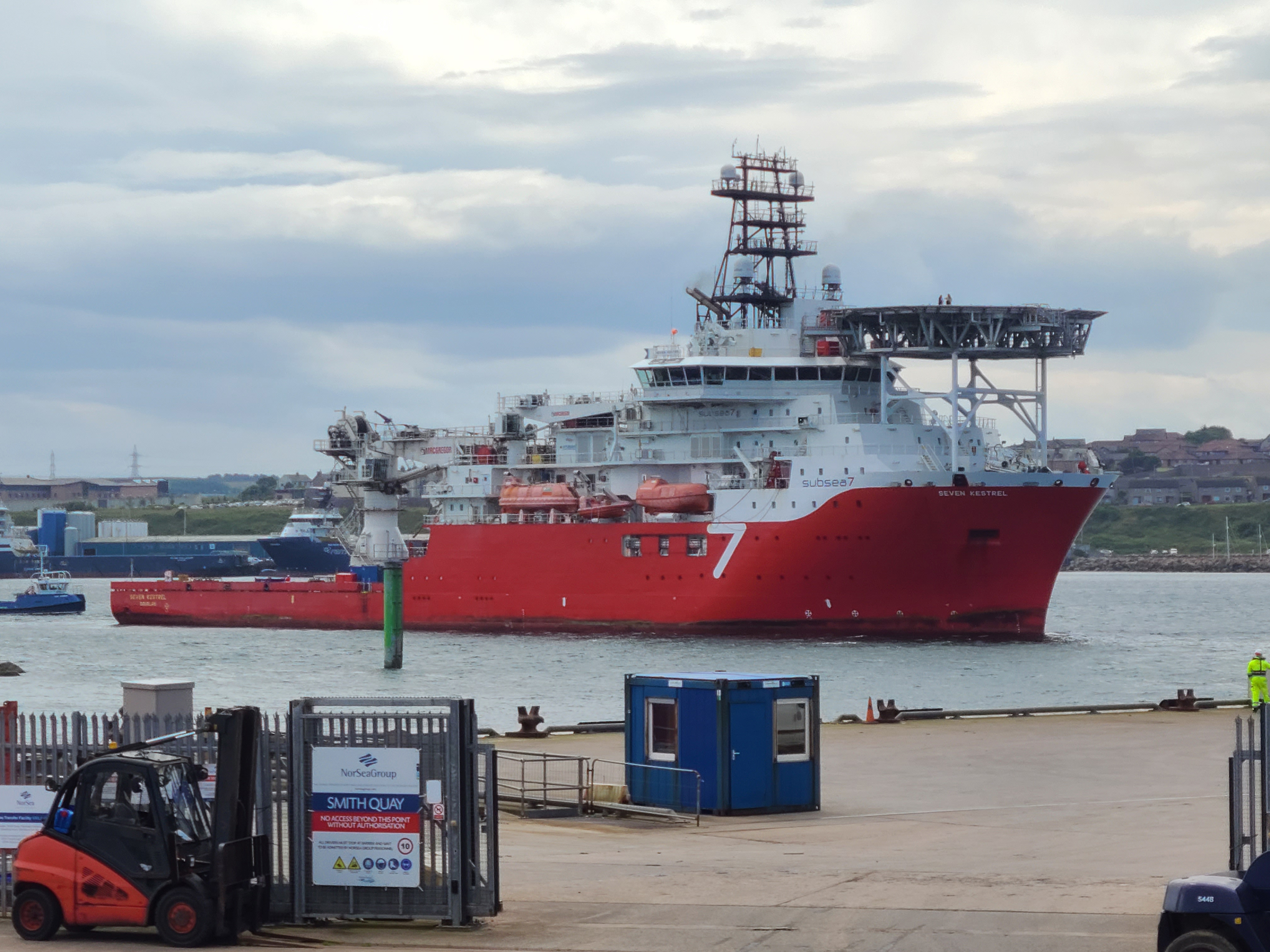 A large red and white ship anchored in calm water.