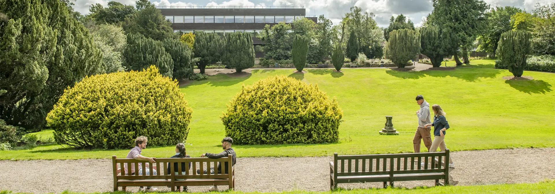 Students chat whilst enjoying the campus in the sunshine