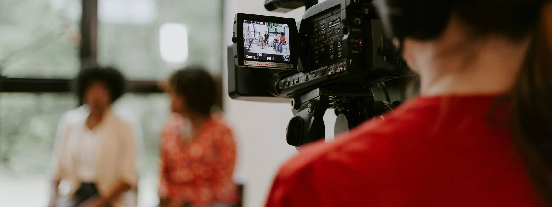 A woman filming a video with a camera, focused and engaged in her creative process.