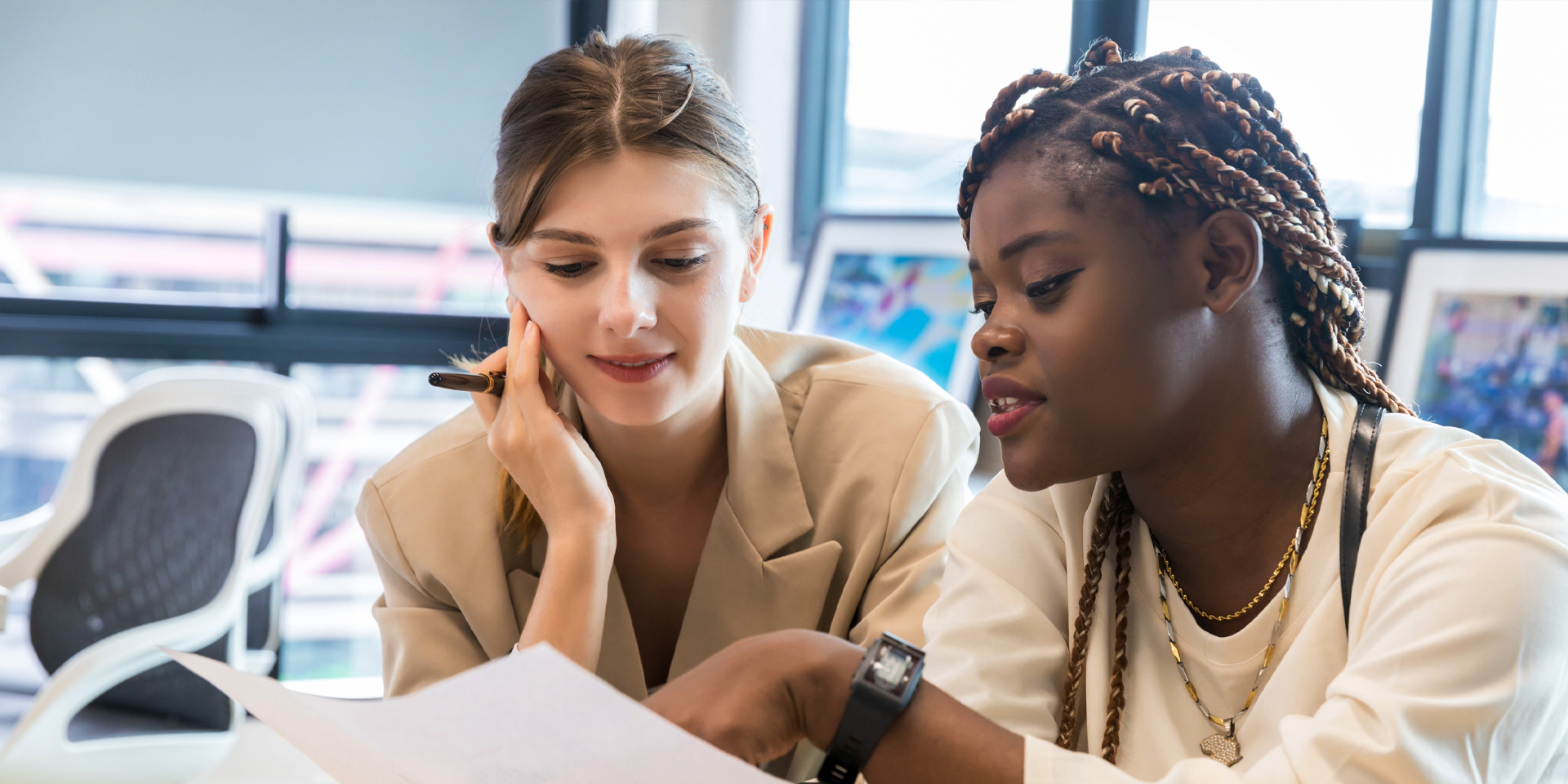 Two women talking at a desk over documents