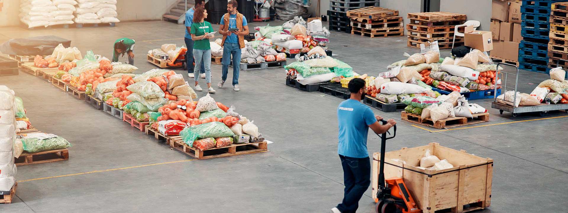 Individuals sorting and handling food boxes in a spacious warehouse setting.