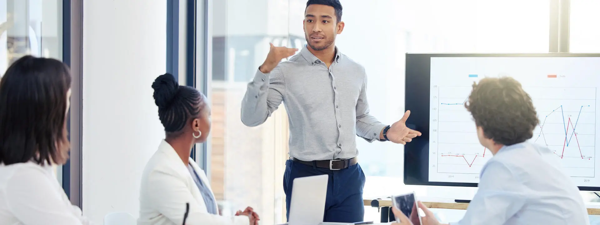 A man presenting to a group of colleagues in a conference room, engaging them with visual aids.