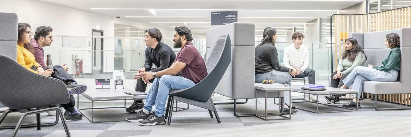 Two groups of seated students in the GRID building break out area.