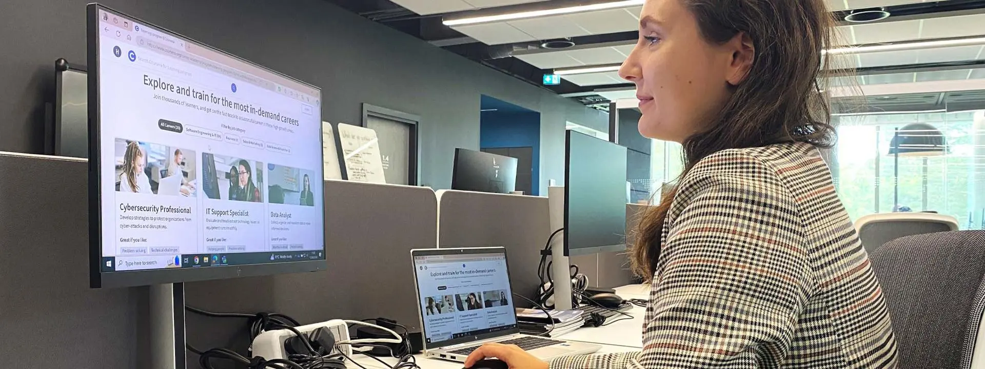 A woman working at a desk focusing on a computer screen.