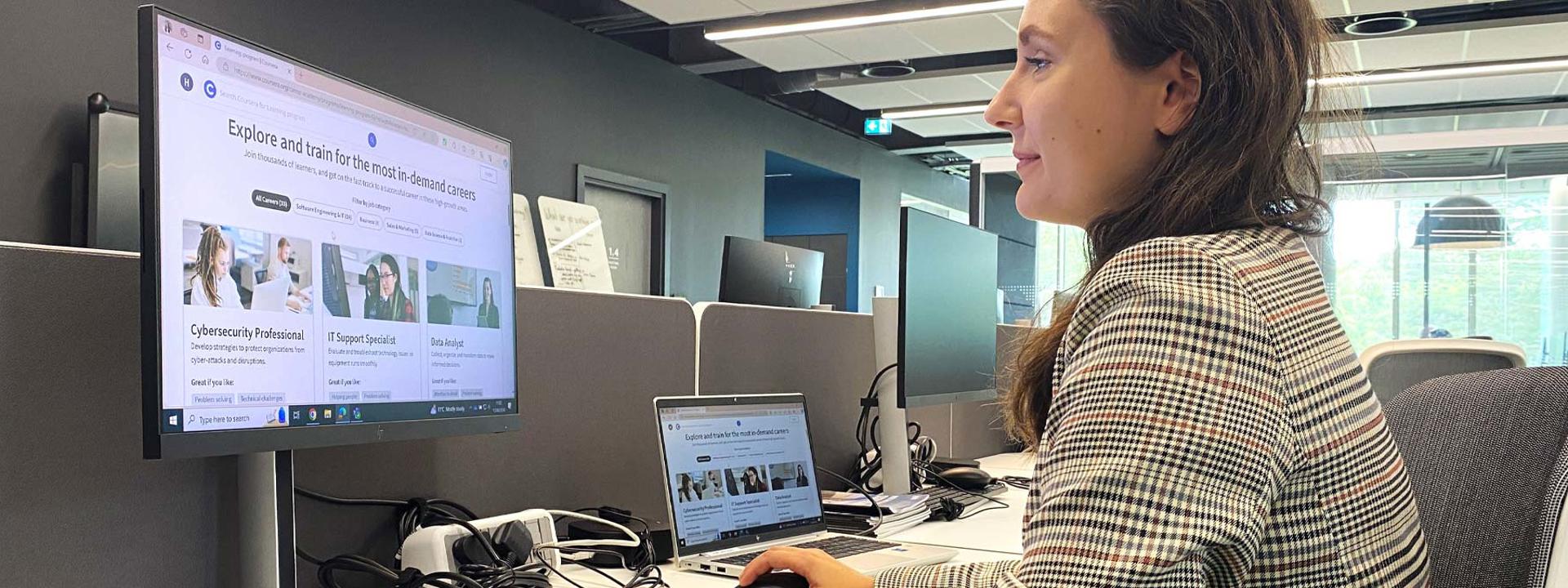 A woman working at a desk focusing on a computer screen.