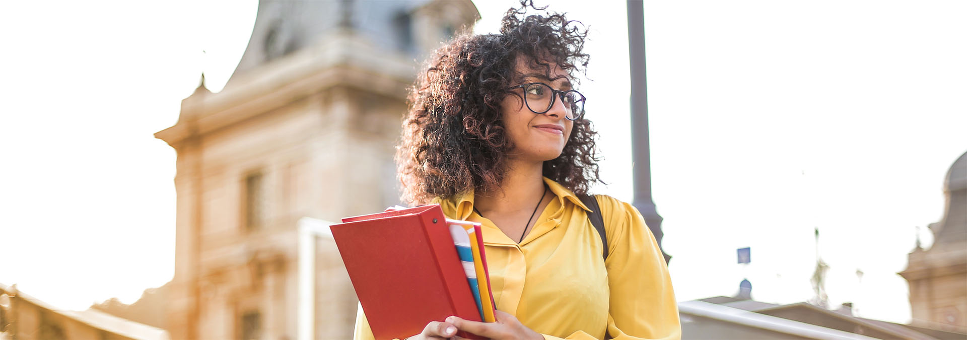 Woman in yellow blouse holding a folder and some notepads