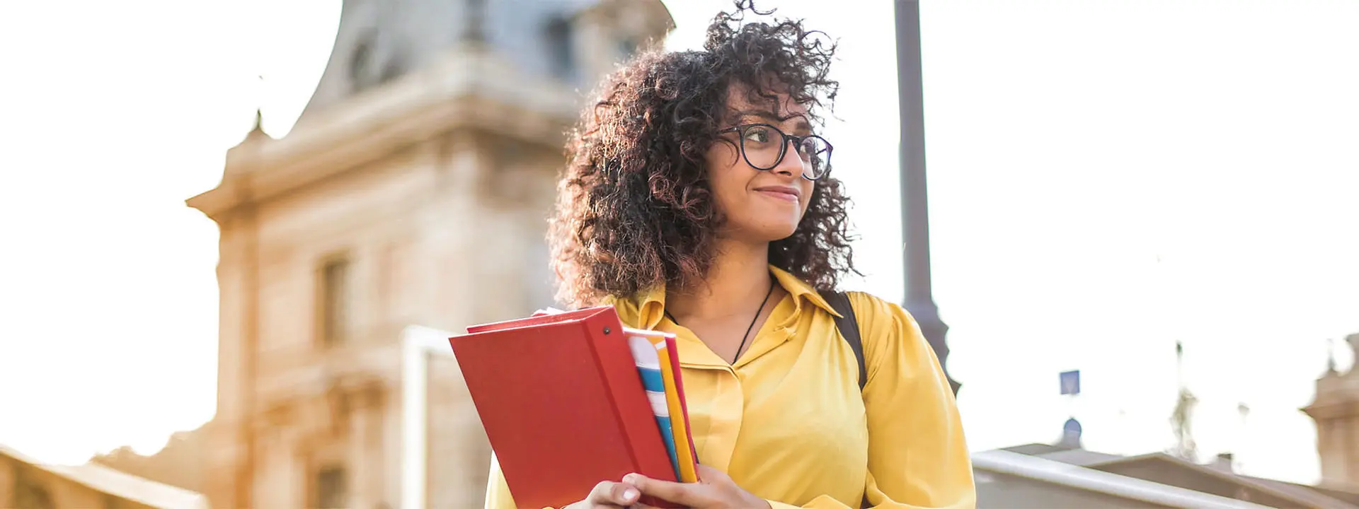 Woman in yellow blouse holding a folder and some notepads