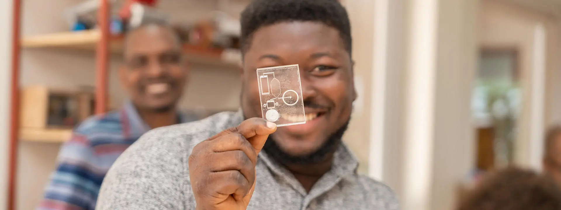 Smiling man holds a diagnostic slide up in front of his face