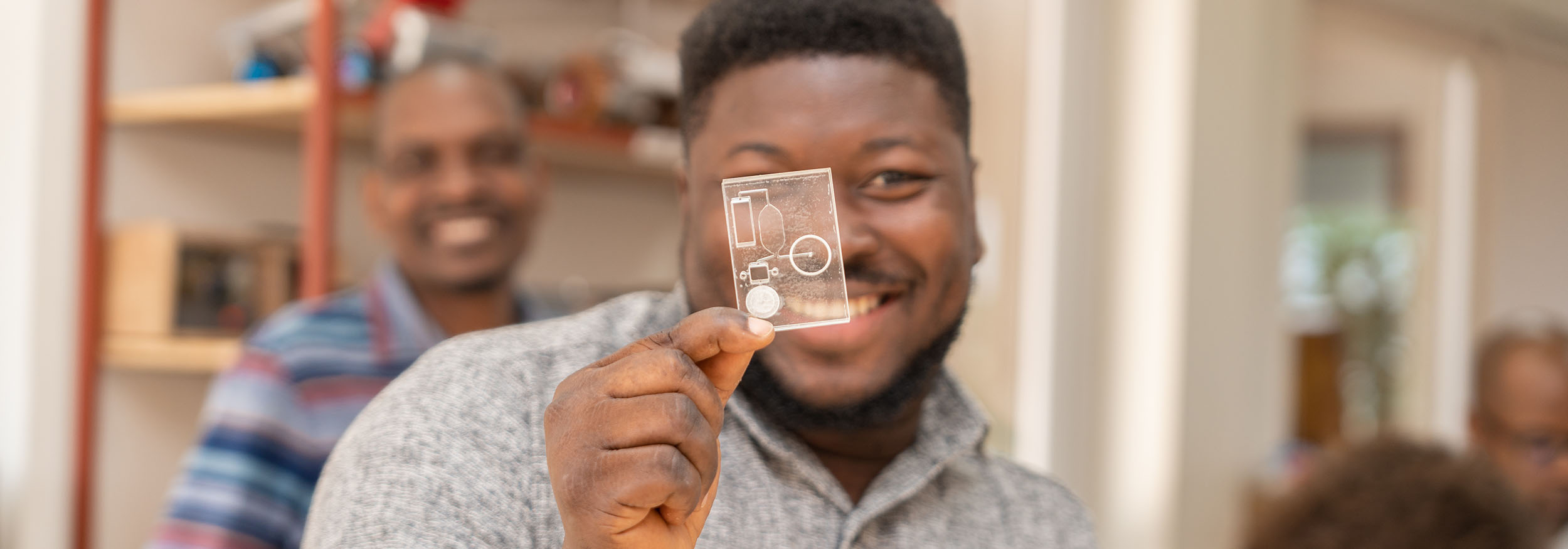 Smiling man holds a diagnostic slide up in front of his face