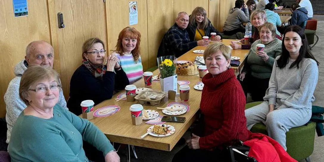 A diverse group of individuals gathered around a table, enjoying a meal together in a warm and inviting setting.