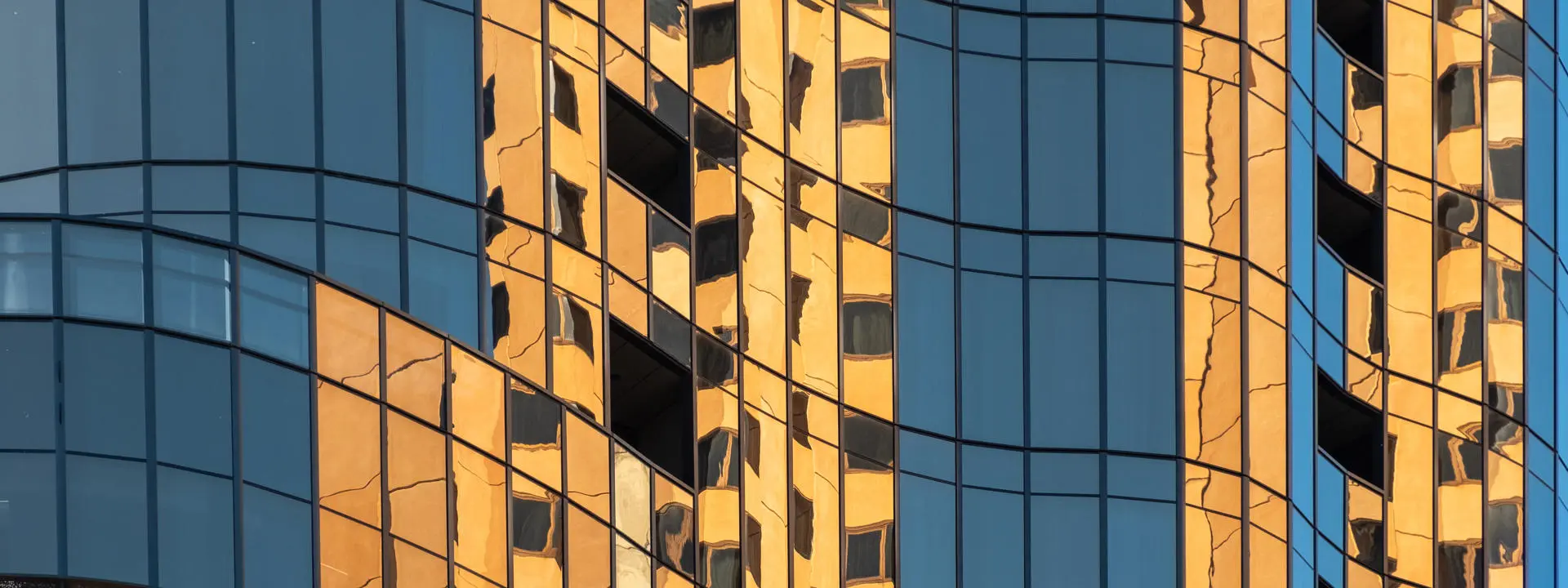 Skyscraper buildings with orange reflected in windows.