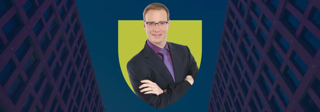 Matthias, our Dual MBA graduate, appears in a Holyrood Green shield with two red skyscrapers on either side of a strip of blue sky in the background.