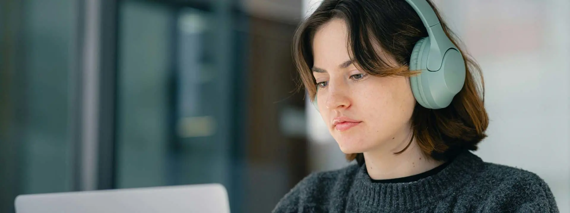 Women wearing headphones works on laptop.