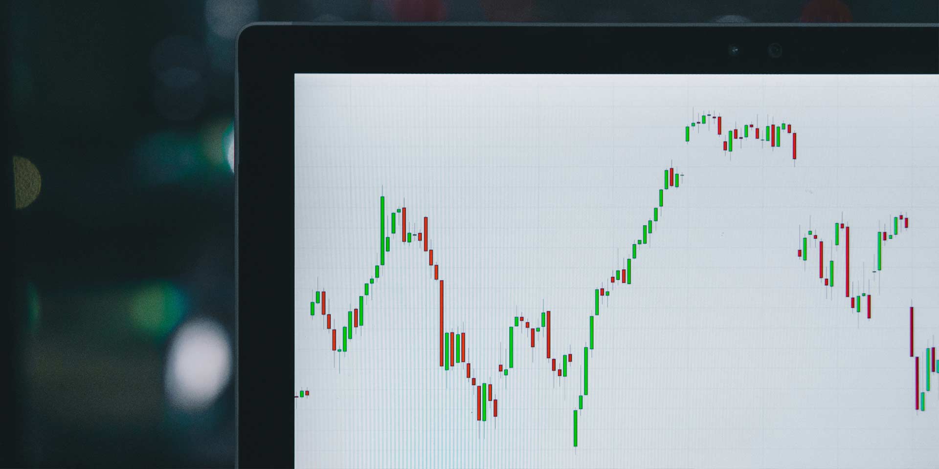 A laptop screen displaying a stock chart with fluctuating lines and data points.