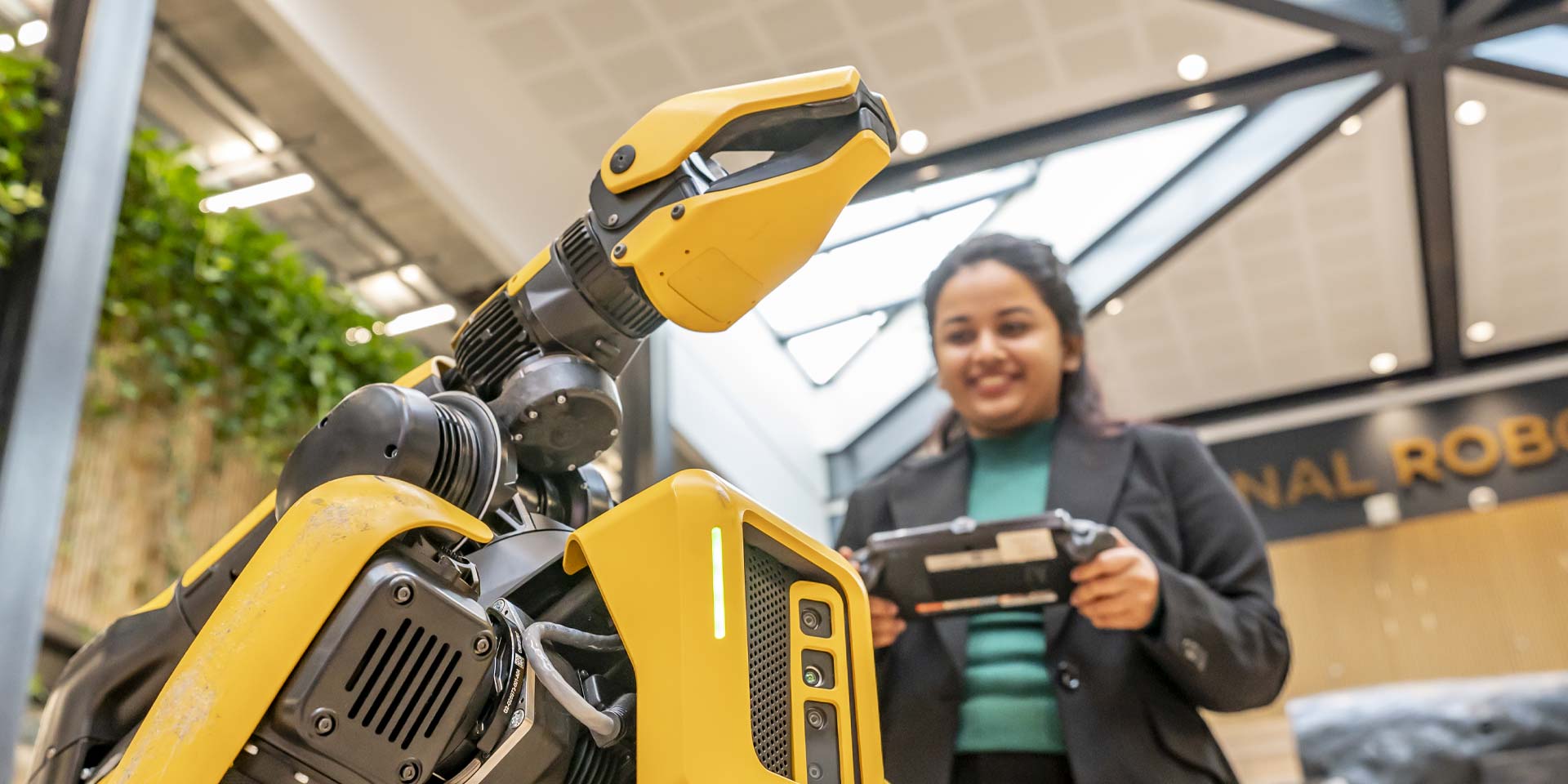 A student controls a yellow and black robot 