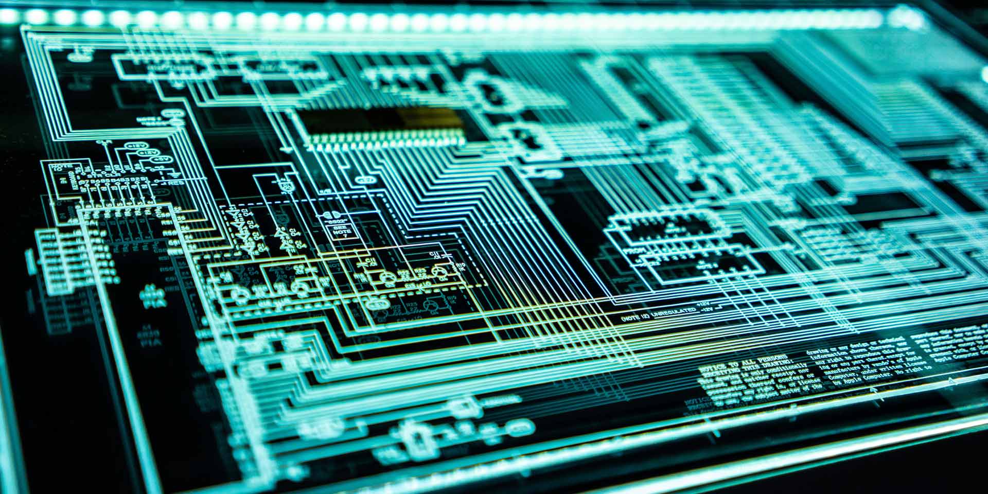 Close-up of a circuit board illuminated by a green glow, showcasing intricate pathways and electronic components.