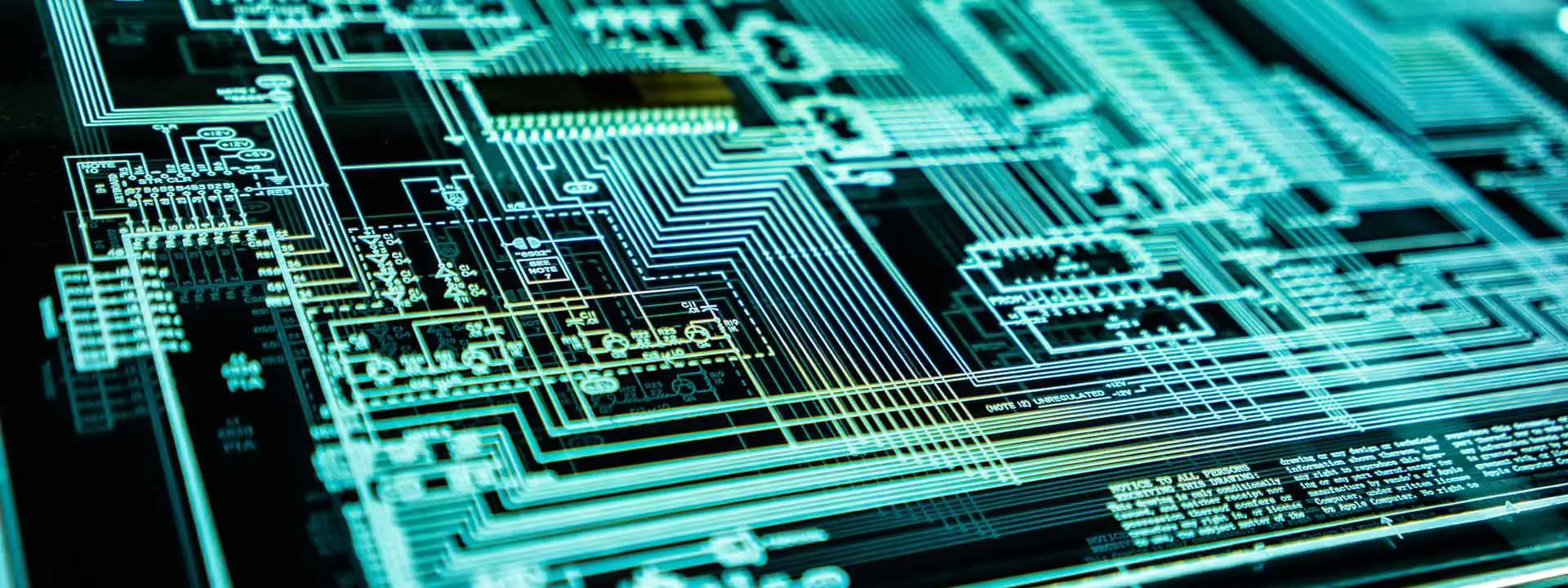 Close-up of a circuit board illuminated by a green glow, showcasing intricate pathways and electronic components.