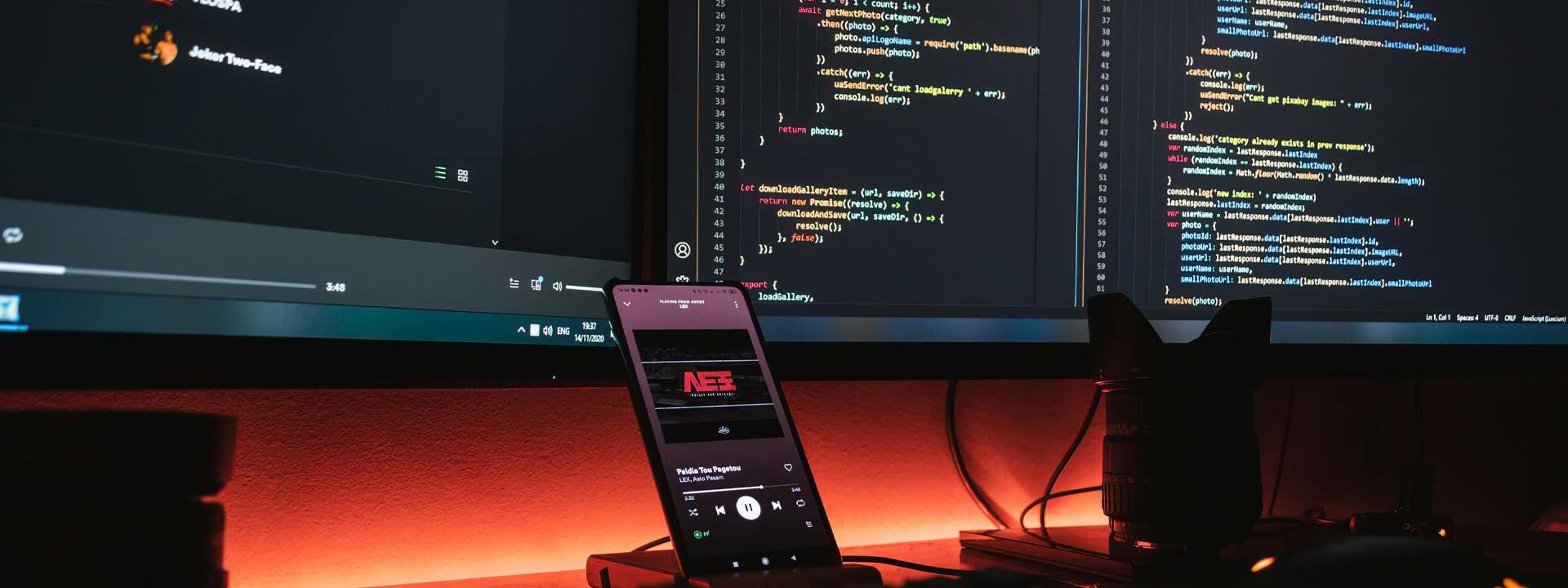 computer monitors with a smartphone positioned in front, representing a blend of technology and communication.