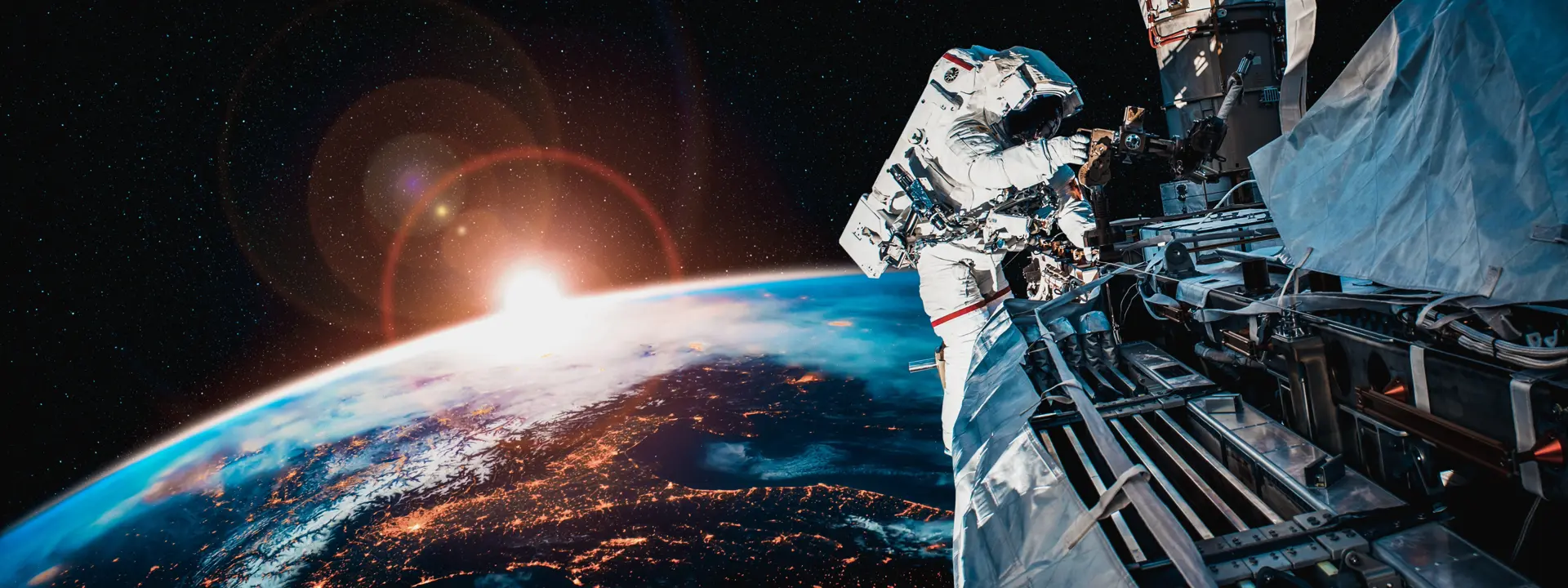 An astronaut works outside a space station with Earth and a glowing sunrise in the background.