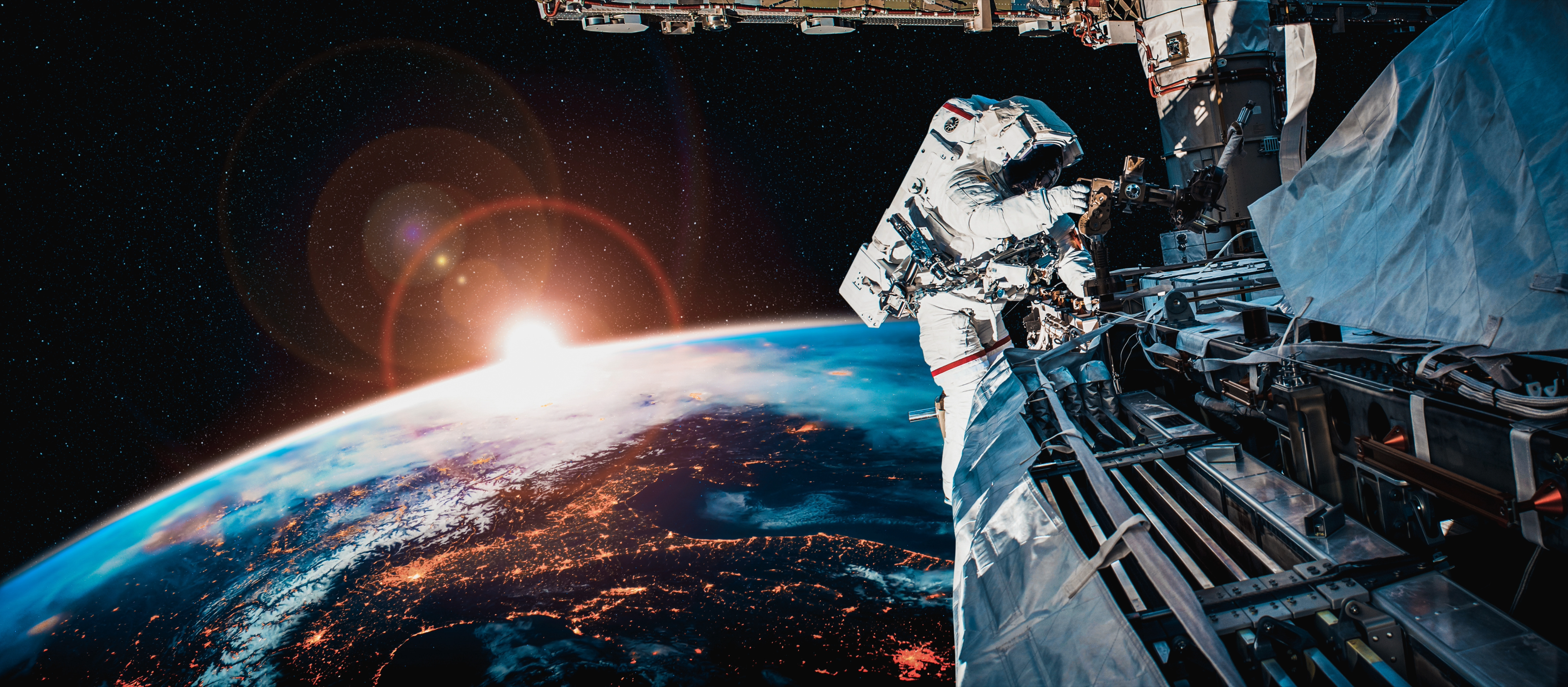 An astronaut works outside a space station with Earth and a glowing sunrise in the background.