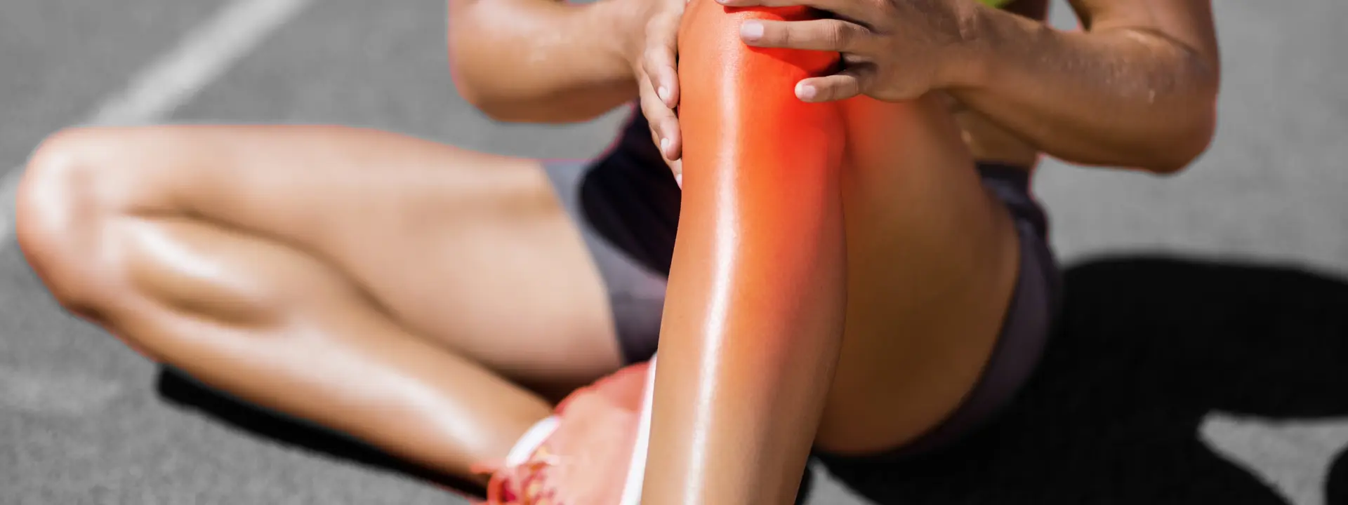 Woman sitting in sports clothes with a sports knee injury.