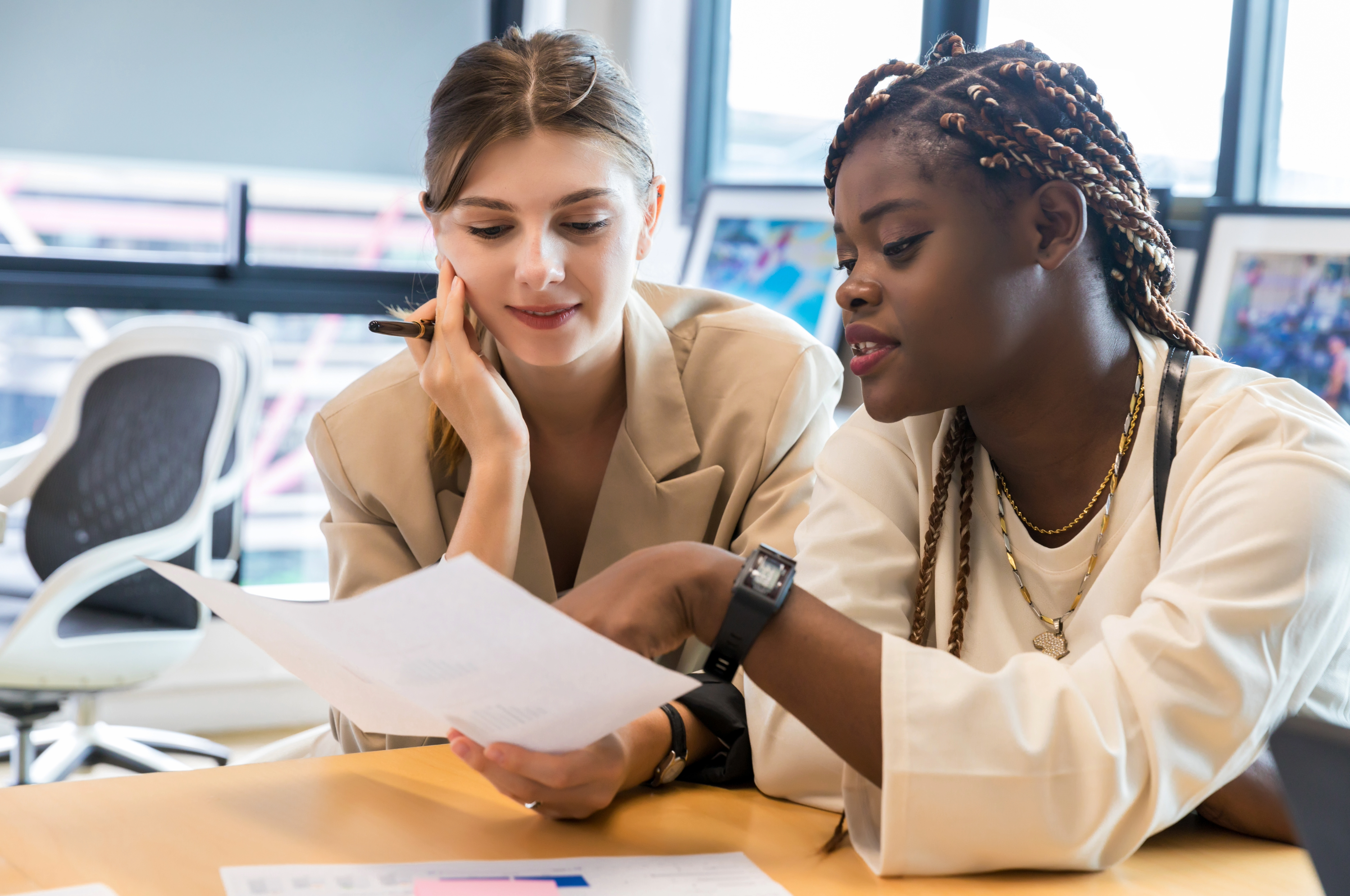 Two women talking at a desk over documents