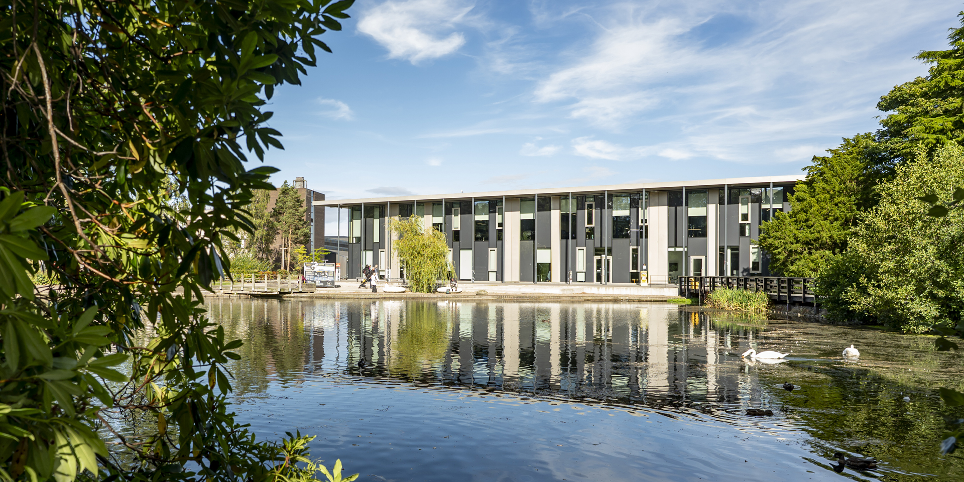 the GRID building reflecting on a serene Loch, surrounded by lush greenery.