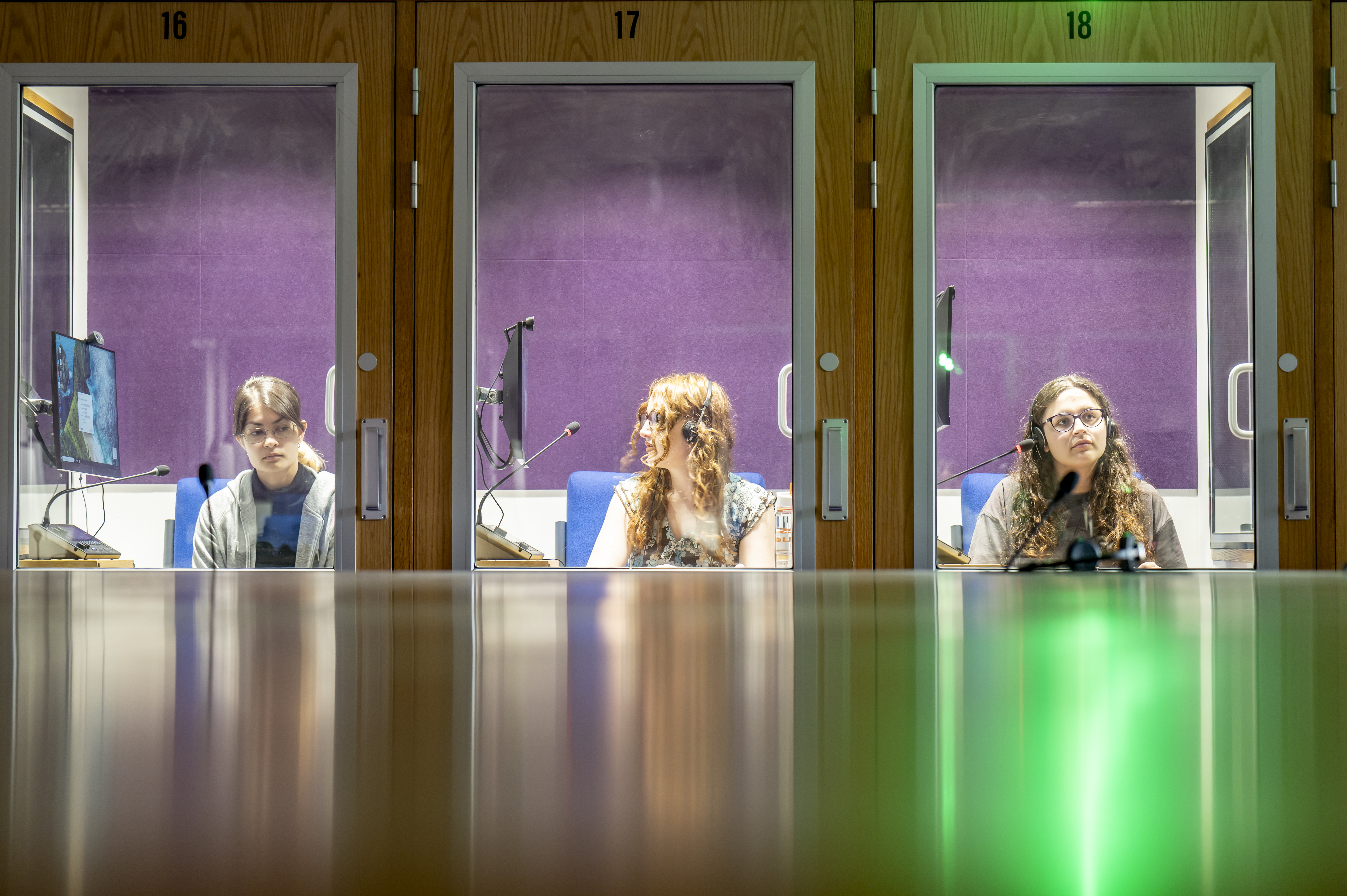 Three female students in individual interpreting booths