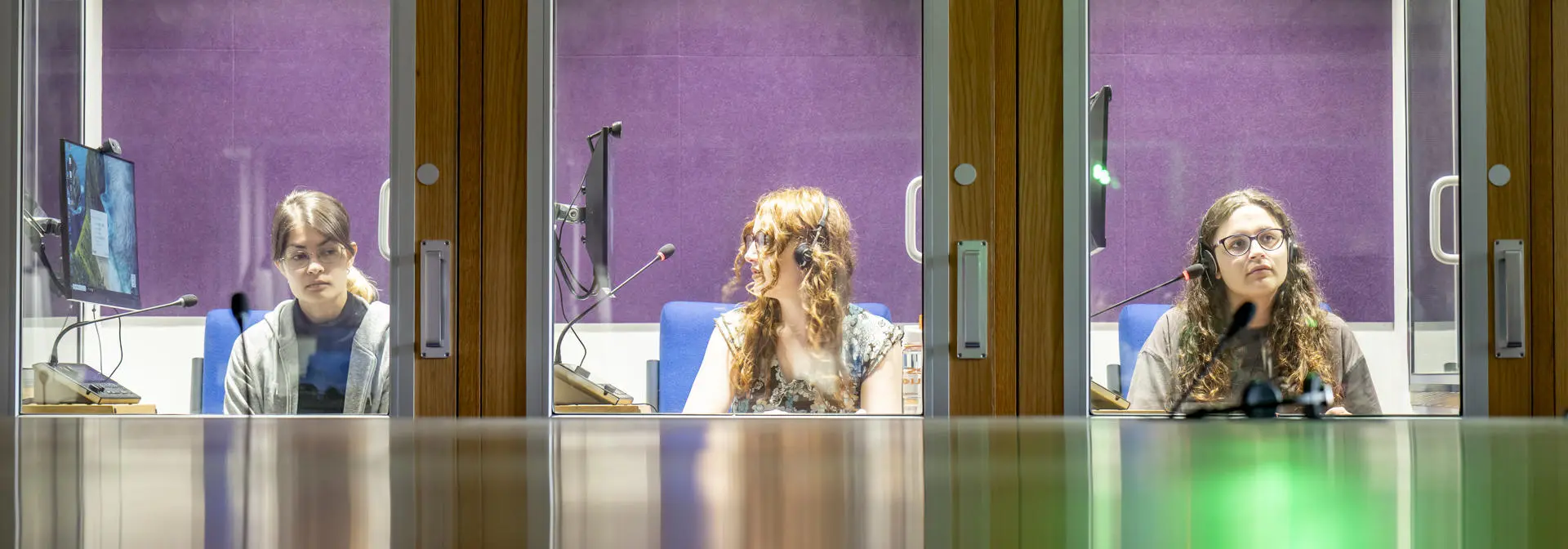 Three female students in individual interpreting booths