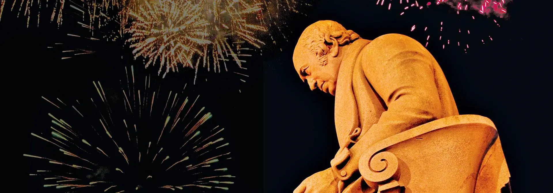The James Watt statue at the Edinburgh Campus lit up by fireworks exploding overhead