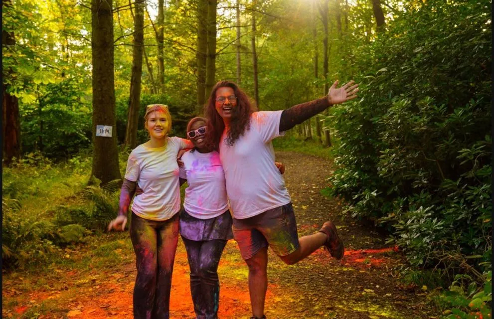 Two people splashed with paint, standing in a park