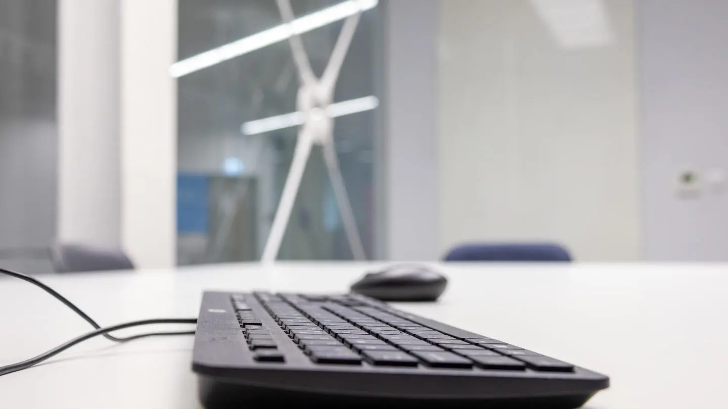 A black keyboard on a white desk in an empty office.