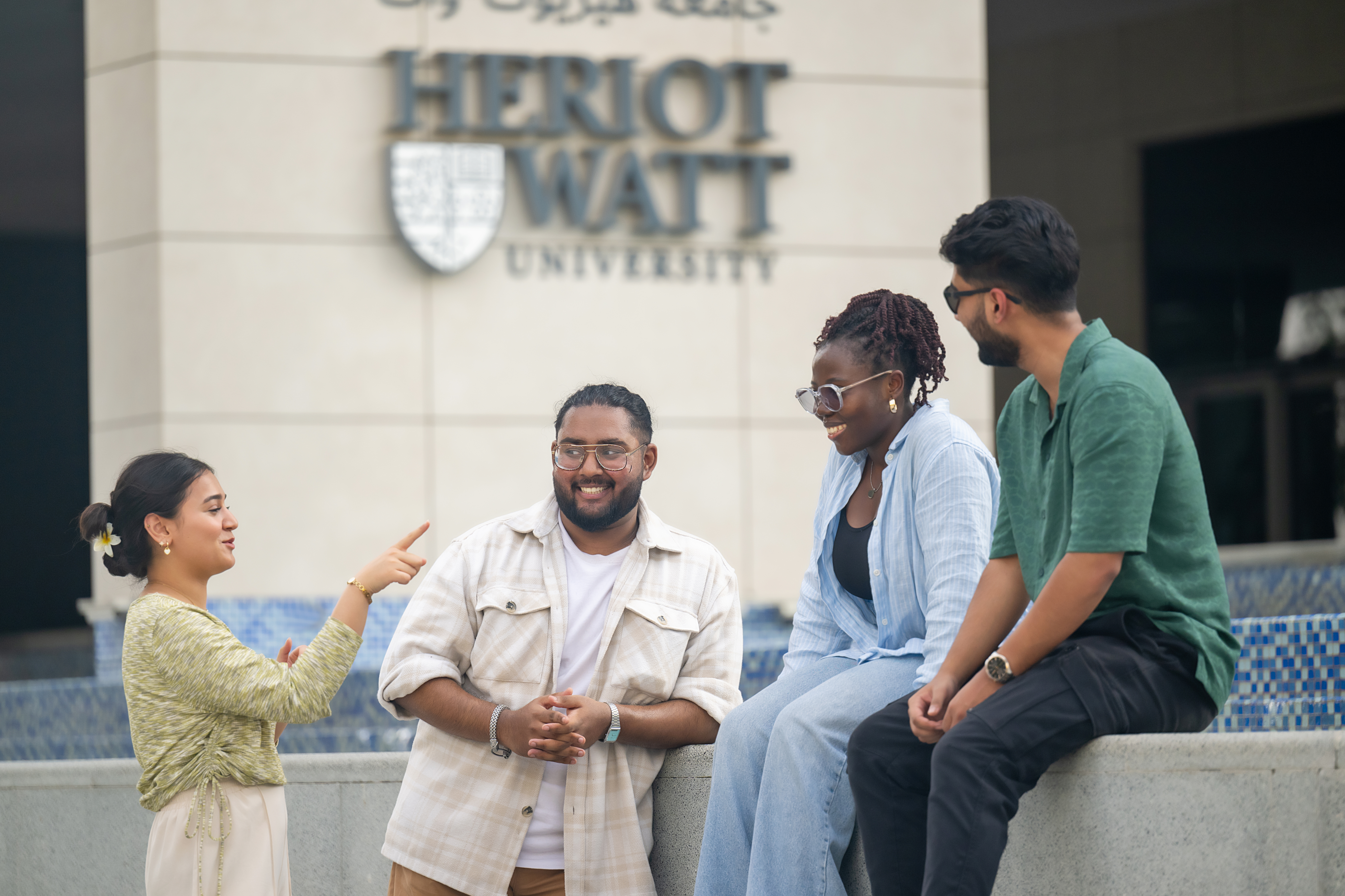 group of students sitting in front of campus and having a fun conversation
